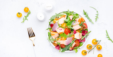 Grilled salmon fish salad with tomato, cucumber, arugula, radicchio, red onion and lettuce with lemon and sesame seeds. Healthy eating delicious lunch. White table background, top viewの写真素材