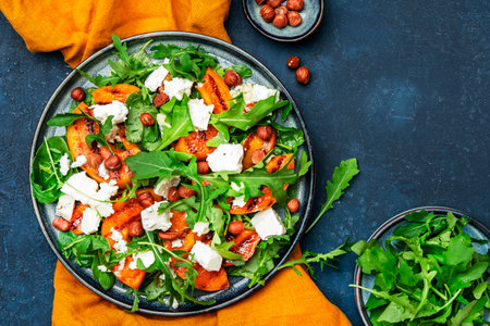 Delicious grilled peach salad with cheese, hazelnuts and arugula on blue background, top viewの写真素材
