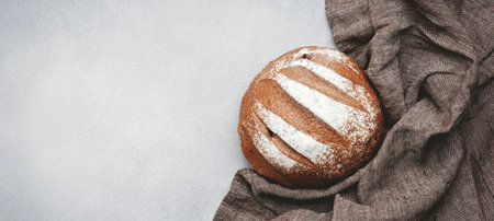 Rye sourdough bread, whole loaf, kitchen linen towel. Gray table background, top viewの写真素材