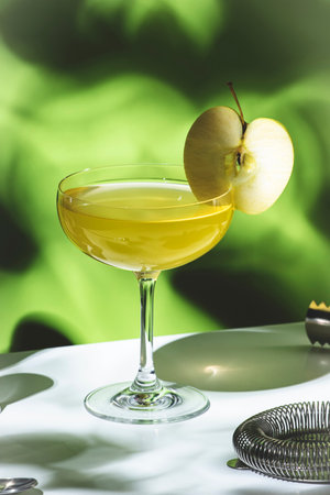 Apple pie alcoholic cocktail beverage with vodka, apple liqueur, cinnamon syrup.. Light green background, hard light, shadow patternの写真素材