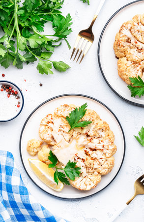 Baked cauliflower steak with garlic butter and spice on plate, white table background, top viewの写真素材