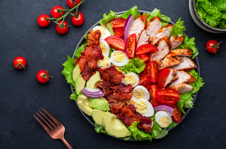 Cobb salad with chicken fillet, tomatoes, eggs, bacon, avocado and lettuce, dark table background, top view. american food dishの写真素材