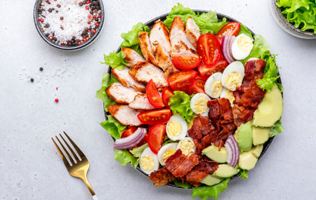 Cobb salad with chicken fillet, tomatoes, eggs, bacon, avocado and lettuce, gray table background, top view. american food dishの写真素材