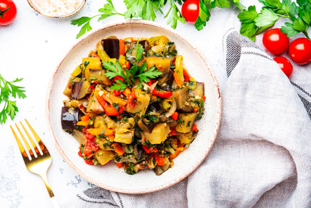 Vegetable stew, saute or caponata. Stewed eggplant with red paprika, tomatoes, garlic, onion, spices and herbs. White kitchen table background, top viewの写真素材