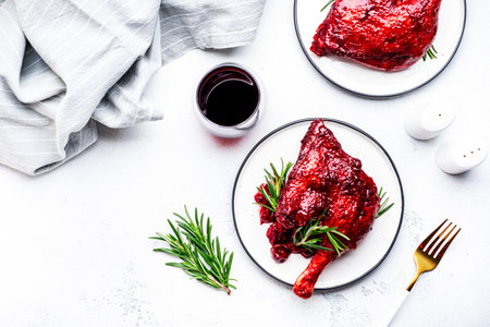 Baked duck legs in cherry and wine sauce with fresh rosemary. Gourmet dinner. White table background, top viewの写真素材