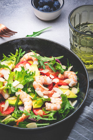 Strawberry, shrimp and herbs salad with arugula, lettuce, avocado and almond slices, gray table. Fresh useful dish for eating healthy. top viewの写真素材