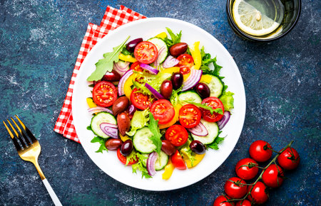Tasty salad with kalamata olives, tomatoes, paprika, cucumber and onion, healthy mediterranean food. Blue table background, top viewの写真素材