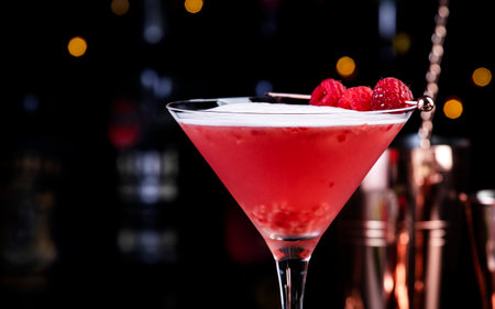 Clover club alcoholic cocktail drink with dry gin, raspberry syrup, lime juice, quail egg white and ice in glass. Black bar counter background, bar tools and bottlesの写真素材