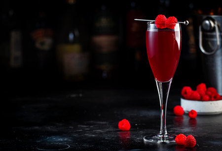 Alcoholic cocktail drink with calvados, prosecco, lychee and raspberry peach puree and ice, dark bar counter background, copy spaceの写真素材