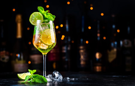Hugo spritz cocktail drink with sparkling wine, elderflower syrup, soda, lime, mint and ice, dark bar counter backgroundの写真素材