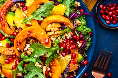 Healthy autumn pumpkin salad with lettuce, arugula, pomegranate seeds and walnuts. Comfort slow food. Blue background. Top viewの写真素材
