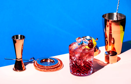Sbagliato Rosa cocktail drink with Italian red liqueur and aperitif, rose sparkling wine with zest, blue bright background, hard light and shadowsの写真素材