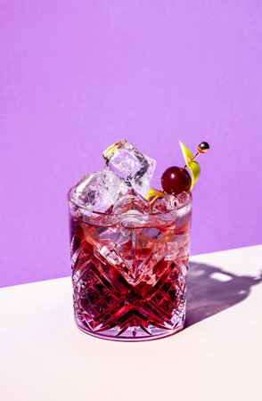 Sbagliato Rosa alcoholic cocktail drink with red liqueur and aperitif, champagne rose or sparkling wine, with zest, purple backgroundの写真素材