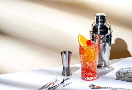 Summer red alcoholic cocktail drink with vodka, liqueur, orange, cranberry, juice, lemon and ice with cherry. Beige backgroundの写真素材