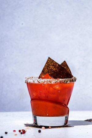 Trendy bloody mary tomato alcoholic cocktail drink with juice, spices, vodka and nori. Gray background, hard lightの写真素材