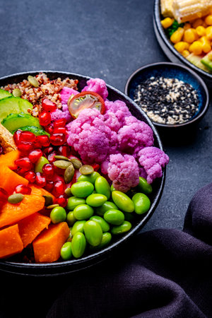Vegan buddha bowl with vegetables, quinoa, edamame, tofu, quinoa and seeds, black background, top...