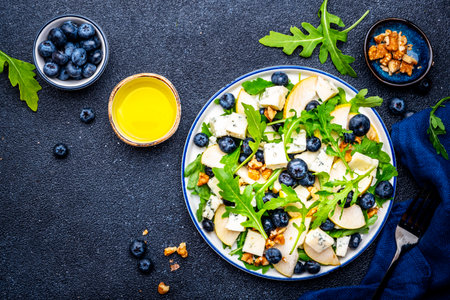 Tasty salad with pears, blueberries, roquefort cheese, arugula and nuts. Black background, top viewの写真素材