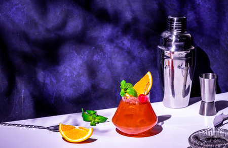 Red orange alcoholic cocktail drink with rum, pineapple juice, syrop, mint, cherry and ice. Purple background, hard lightの写真素材