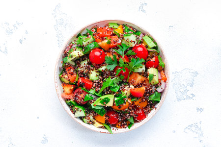 Quinoa vegan salad with avocado, tomatoes, onion and parsley, white background, top viewの写真素材