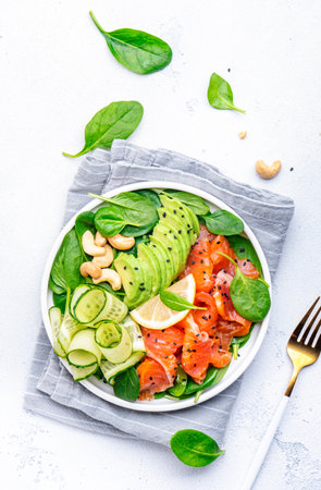 Salad with salted almon, avocado, spinach, cucumber, sesame and cashew. White background, top viewの写真素材