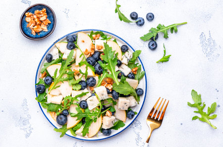 Salad with pear, blueberries, blue cheese, arugula and walnuts. White background, top viewの写真素材