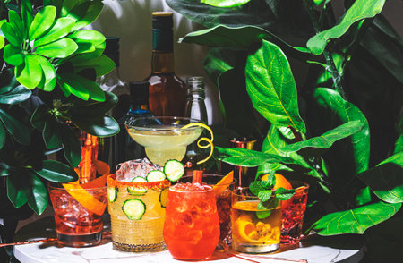 Spring alcoholic cocktail party with ready-made cocktails, bar tools and bottles of spirits on...