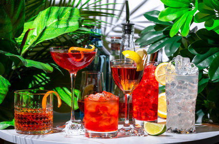 Summer alcoholic cocktail party with ready-made cocktails, bar tools and bottles of spirits on...