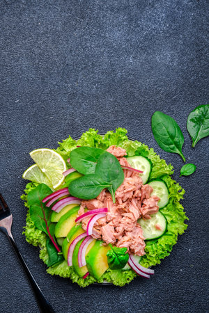 Tuna and avocado salad with lettuce. Black background, top view