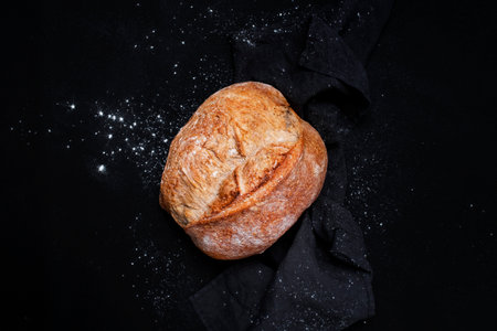Homemade whole grain freshly baked bread. Black background, top view