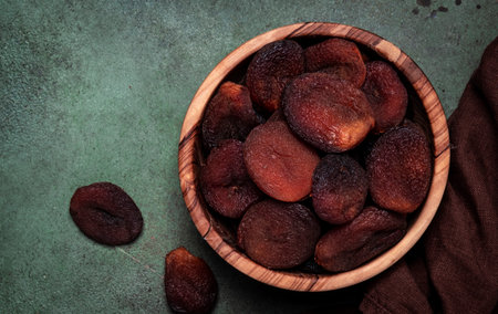 Sundried dried apricots in bowl on green background, top viewの写真素材