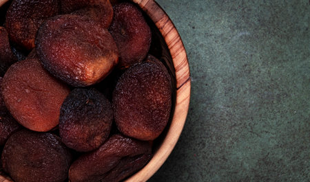 Sundried dried apricots in bowl on green background, top viewの写真素材