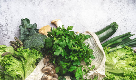 Fresh Food Background. Reusable Eco Fabric Bags for Storage with Green Vegetables, Cabbage Broccoli, Avocado, Mushrooms on Gray Table, Top Viewの写真素材