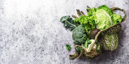 Fresh Food Background. Eco string bag with green vegetables, broccoli, avocado, mushrooms on gray table, top viewの写真素材