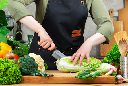 Chef cooking food in the kitchen. Cook organic cuts Chinese cabbage. Wooden table, kitchenware, vegetables, herbs and ingredients. Healthy vegan eating, recipes, bloggingの写真素材