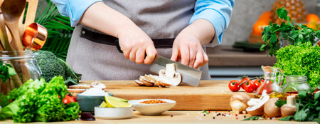 Cooking Food in the Kitchen. Chef cuts mushrooms. Cozy kitchen with wooden table, kitchenware,...