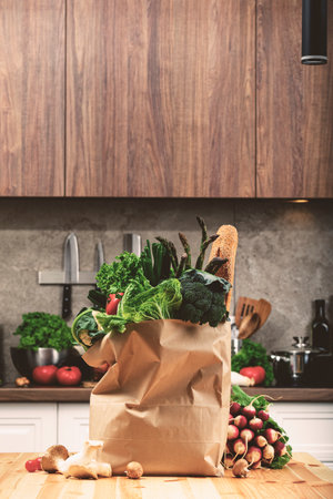 paper bag with fresh organic vegetables on wooden table in kitchen. Colors and textures from various vegetables create healthy and inviting atmosphere for cooking.の写真素材