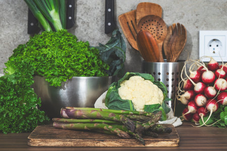 A beautiful kitchen showcases fresh vegetables and herbs gathered for meal preparation, promoting a healthy and eco-friendly lifestyle.の写真素材