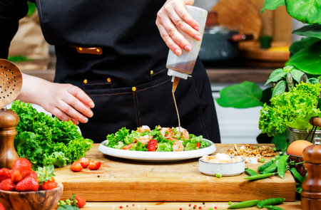 passionate chef artfully prepares colorful vegetable salad while drizzling dressing in bright kitchen filled with greenery.の写真素材