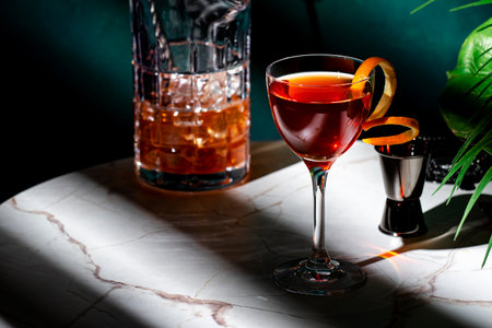 Elegant cocktail on a marble table with a pitcher and garnish, showcasing a refined drink in a chic settingの写真素材