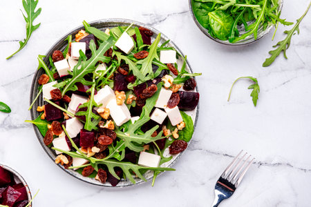 Gourmet beet salad with soft cheese, arugula, raisins and walnuts, marble table background, top viewの写真素材