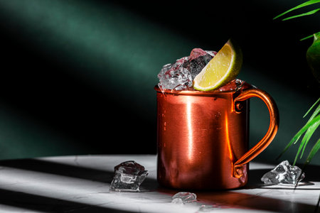 London mule alcoholic cocktail drink with gin, lime juice and ice. Green background, hard lightの写真素材