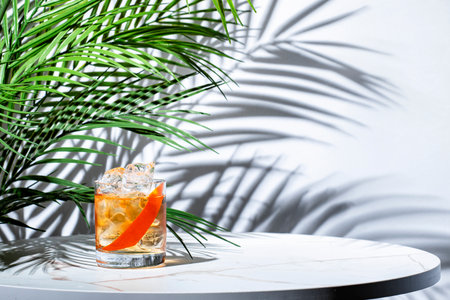 Refreshing cocktail served with ice, grapefruit twist, and hints of vodka, aquavit, and scotch whiskey amidst lush tropical decorの写真素材