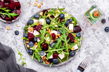 Gourmet salad with beet, blueberries, cheese, arugula and walnuts, gray table background, top viewの写真素材
