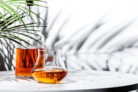 Japanese single malt whiskey glass next and bottle, with decorative plant shadows creating a sophisticated ambiance.の写真素材