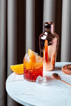 Negroni sbagliato cocktail served on a marble table with orange slices and a cocktail shaker in soft lightingの写真素材