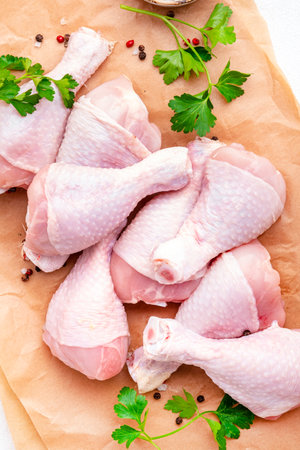 Raw chicken legs on parchment with pepper, salt and parsley. Top viewの写真素材