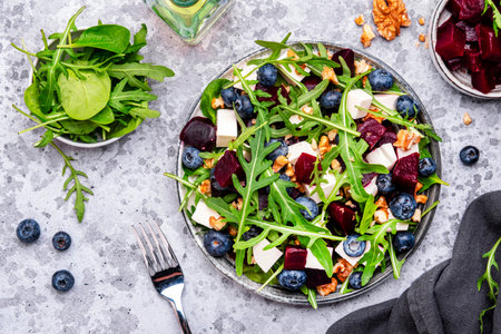 Gourmet salad with beet, blueberries, cheese, arugula and walnuts, gray table background, top viewの写真素材