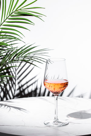 refreshing rose pink wine on a marble table with tropical backdrop for a relaxing momentの写真素材