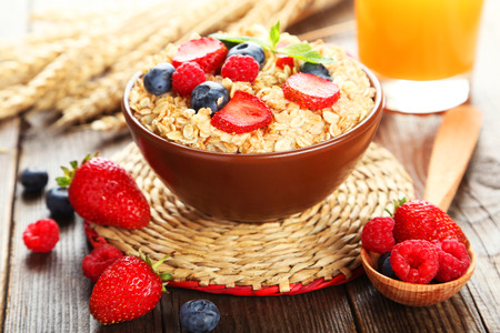 Oatmeal with berries on brown wooden backgroundの写真素材