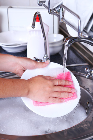 Female hand with sponge washing dishの写真素材